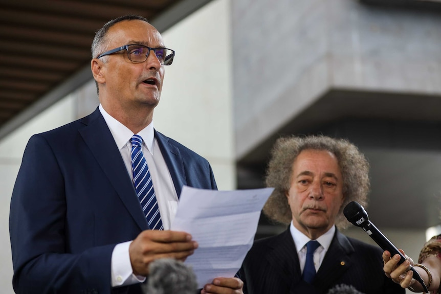 Ardent Leisure CEO John Osborne holds a piece of paper and reads a statement outside the Brisbane Magistrates Court.