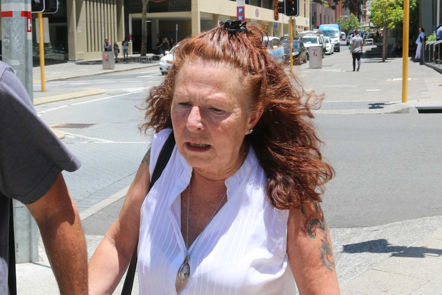 A woman holding a man's hand walks down the road outside court.