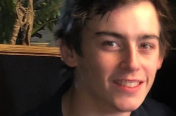 A teenage boy smiles after a photo.