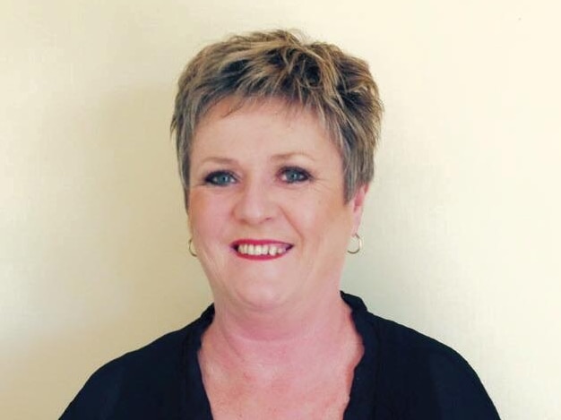 A woman with short hair smiles while posing for a portrait.