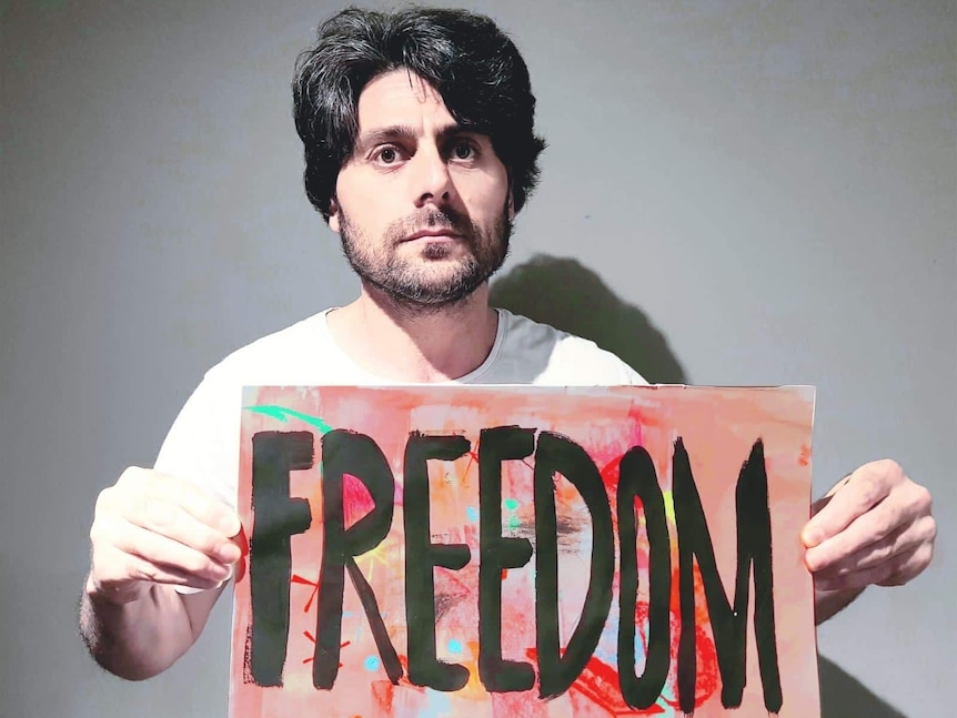 Farhad holding a painted sign saying 'freedom'.