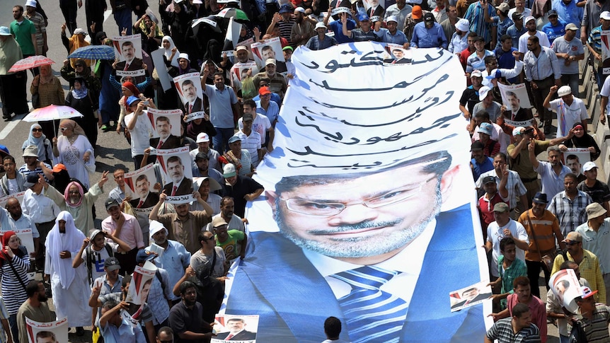 Egyptian supporters of deposed president Mohammed Morsi carry a giant poster bearing his portrait