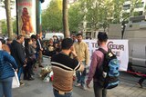 Tourists take photos at Paris shooting scene.