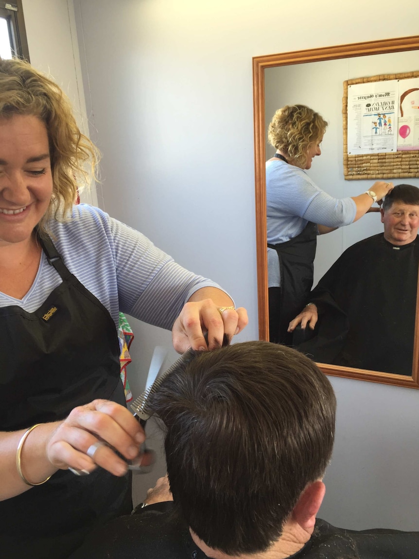Hairdresser Brooke Nevill cuts a client's hair at Warrnambool livestock exchange.