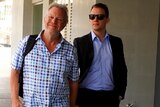 An older man on the right wearing a chequered shirt and jeans leaves court with Alister Swift dressed in a suit and sunnies.