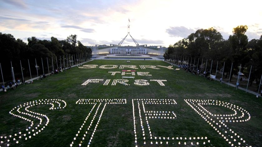 Candles form the words 'Sorry, The First Step' outside Parliament House