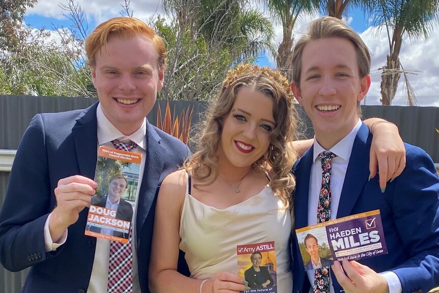 Two males and a female standing in fancy dress holding local government election pamphlets