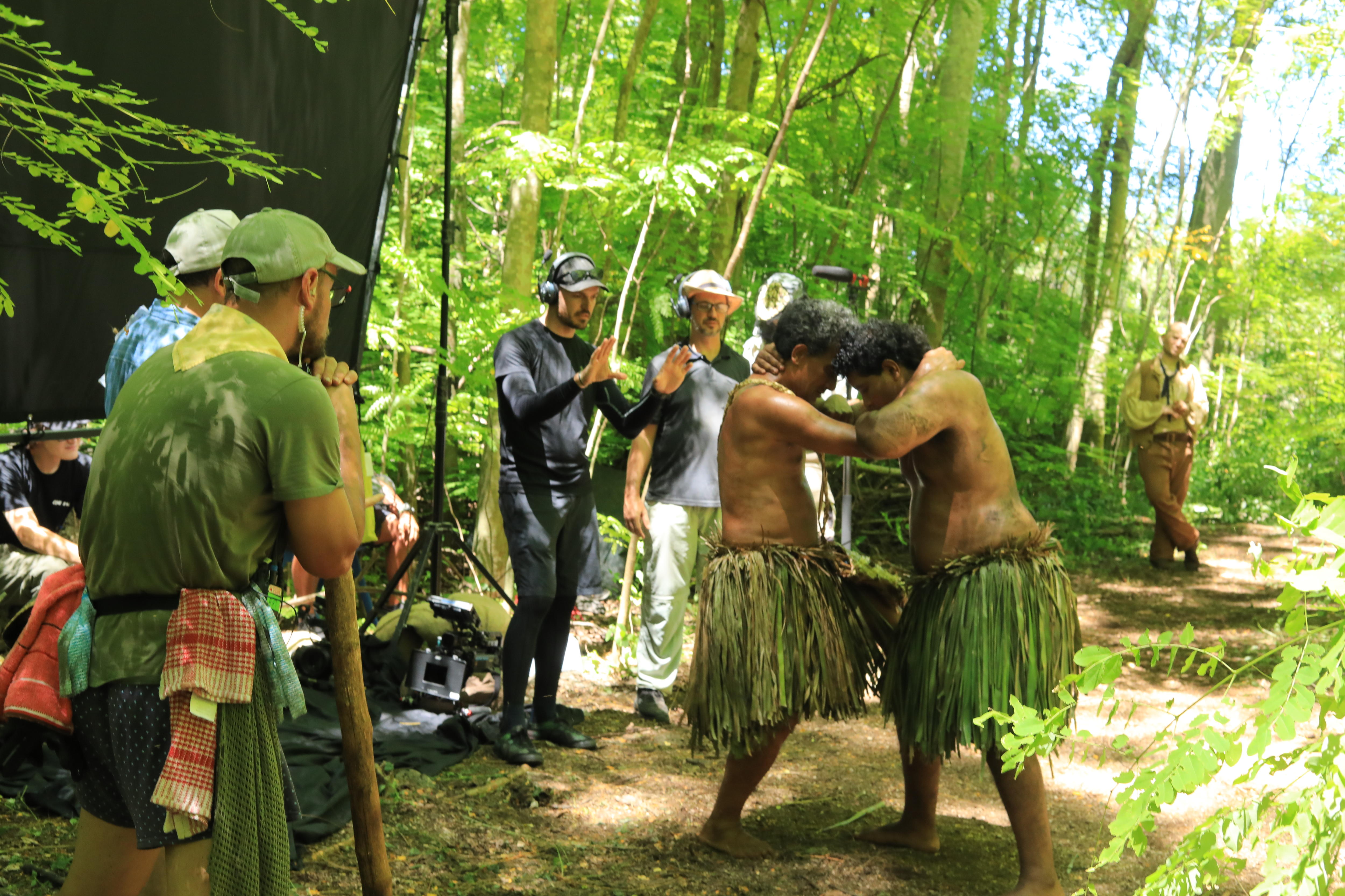 Two men wearing traditional wear from Naoero hug onset. Men with cameras film around them.