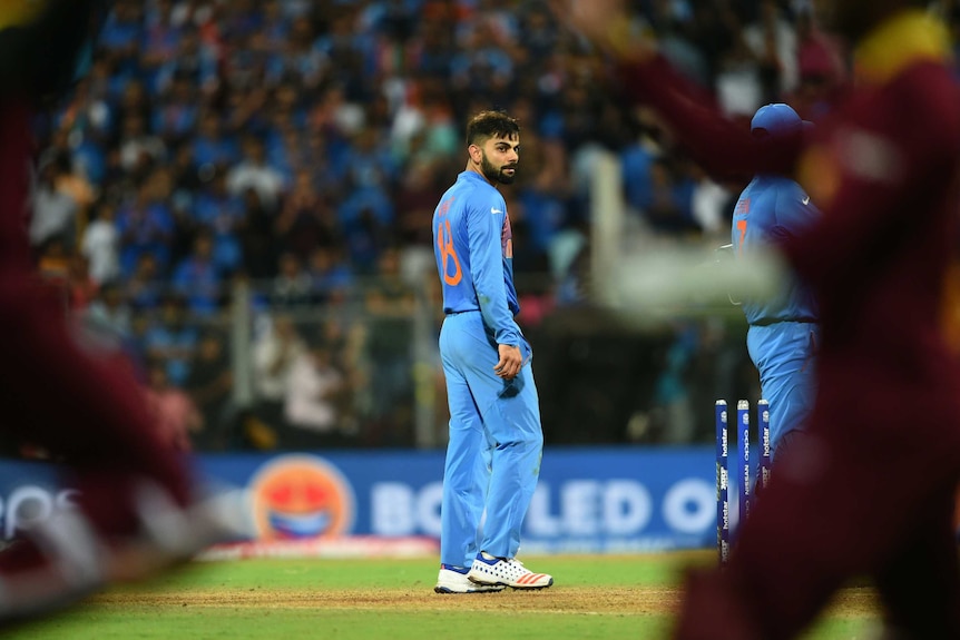 West Indies players' celebrations are watched by India's Virat Kohli (C) after World T20 semi-final.