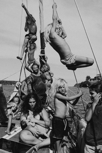 Black and white photograph of large family on boat, mother breastfeeding in centre of the scene.