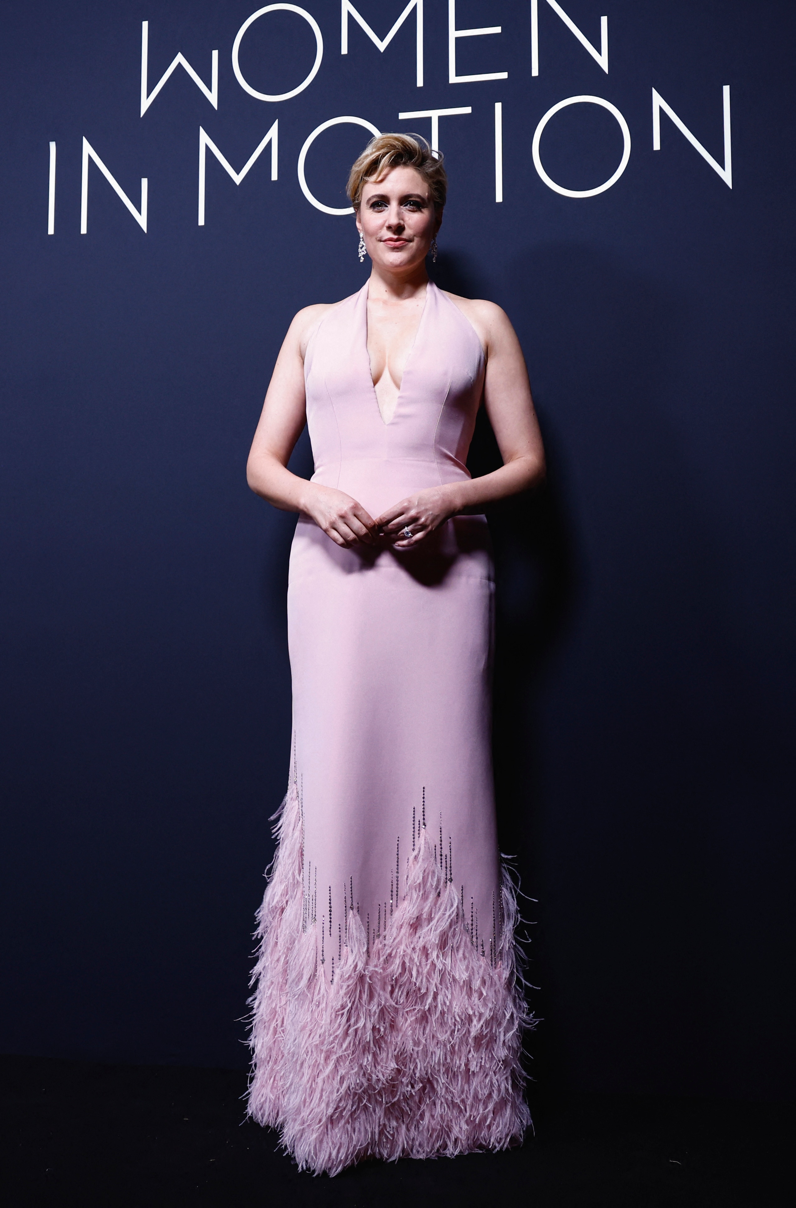Greta Gerwig wearing a pale purple halter dress with feathery fringing at the bottom
