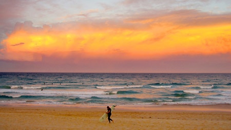 Sunset over Manly beach, a surfer silhouetted in the distance