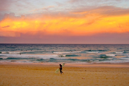 Sunset over Manly beach, a surfer silhouetted in the distance