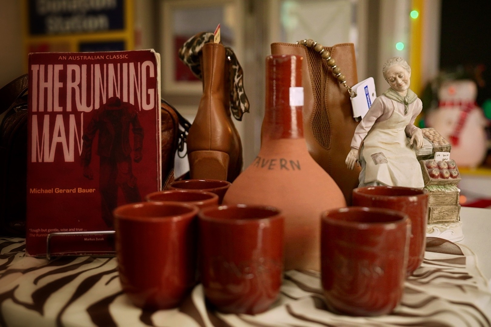 Uma exposição avermelhada de xícaras de café usadas ao lado de um livro chamado The Running Man