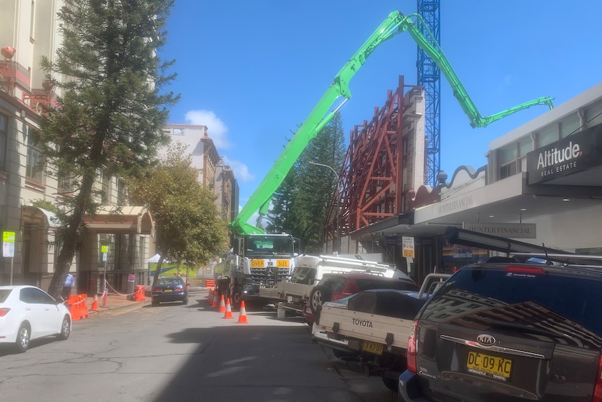 A large crane set up on a city street hangs over a construction site.