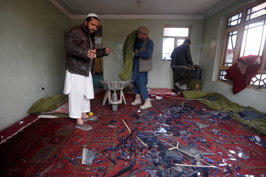 Men clear broken windows from their office in Kabul