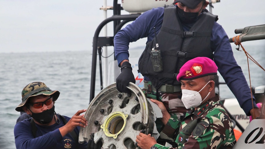 Indonesian Navy divers show parts of an aircraft recovered from the water
