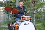 Howie Johnstone plays his drums in front of a metal fence guarding his Yarloop property.