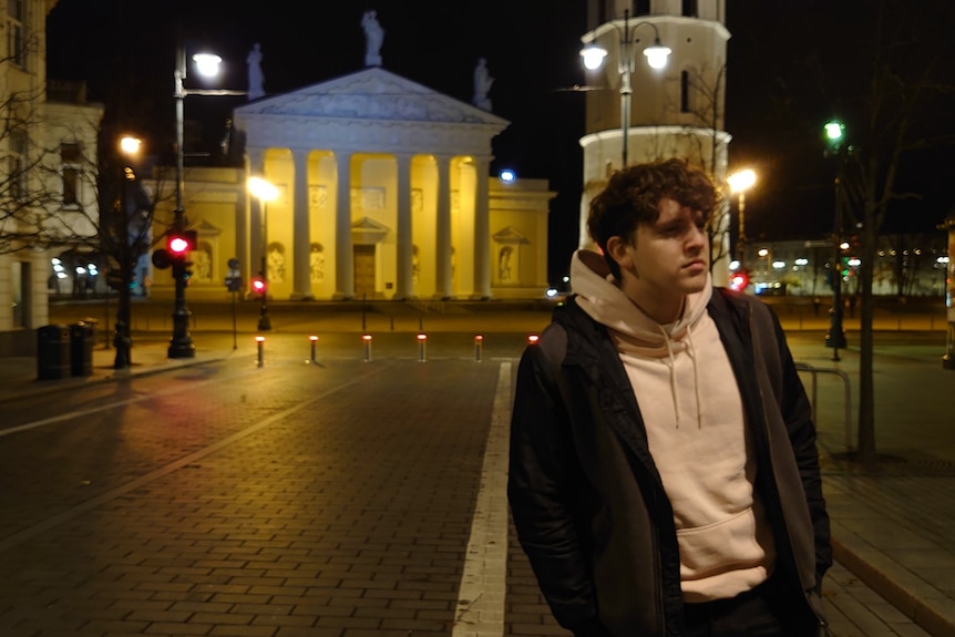 A young man in a hoody with a Lithuanian street in the background