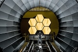 Man stands in front of telescope mirrors 