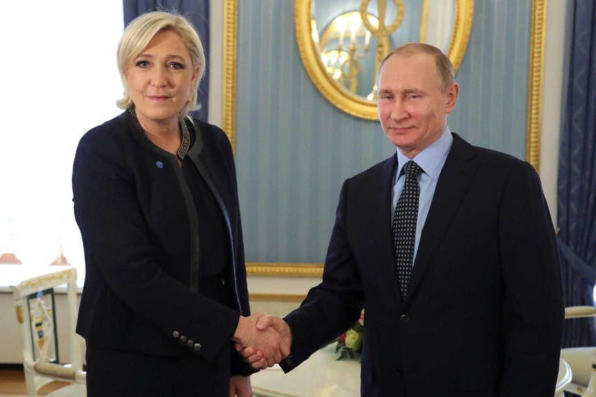 Russian President Vladimir Putin shakes hands with Marine Le Pen