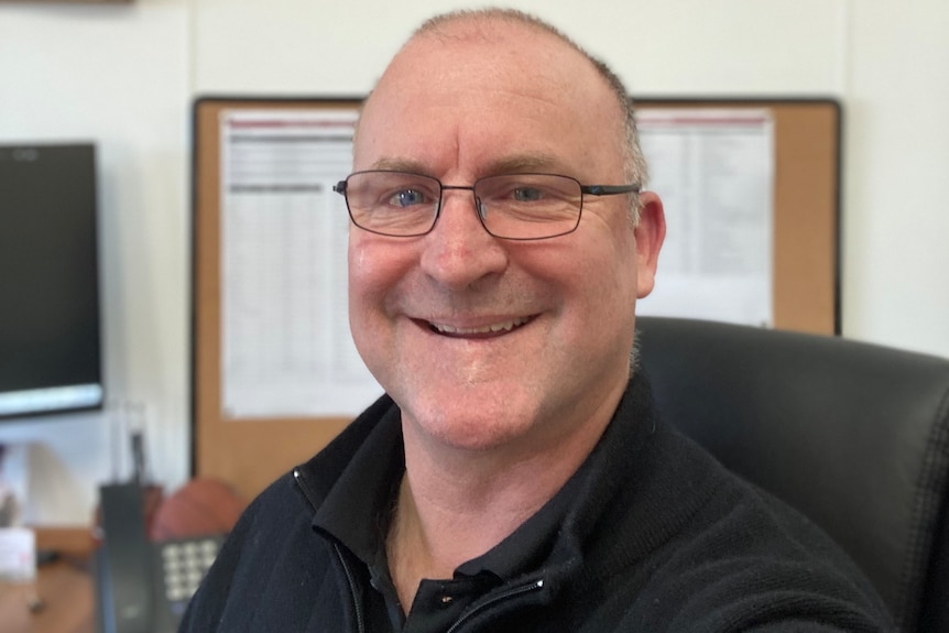 Dan McKinna smiles, sitting at a desk.