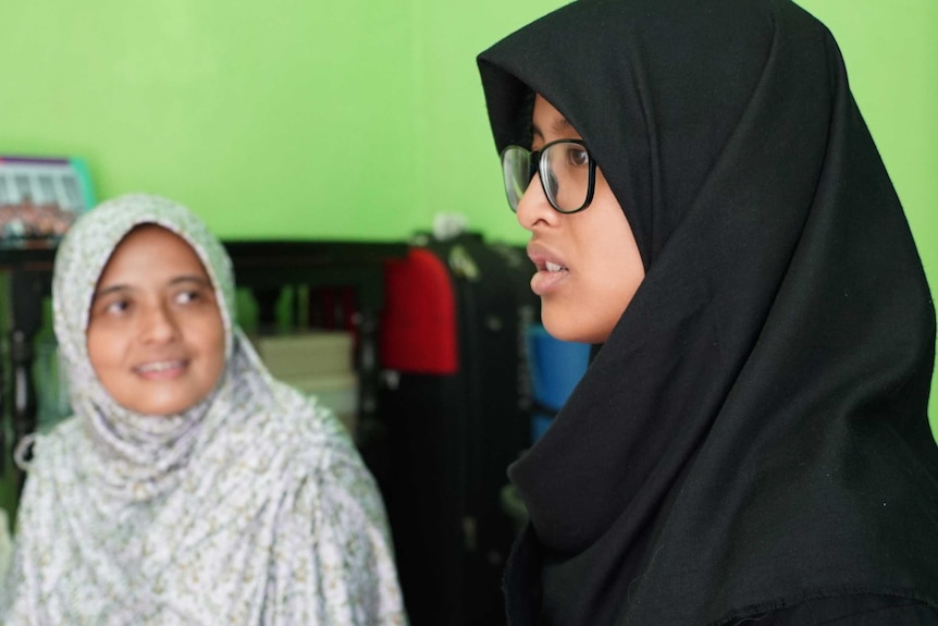 Indonesian schoolgirl Nur Dhania talks while her mother listens in the background