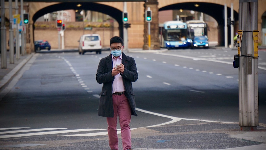 封城期间，一位戴着口罩的行人独自走在悉尼街头。