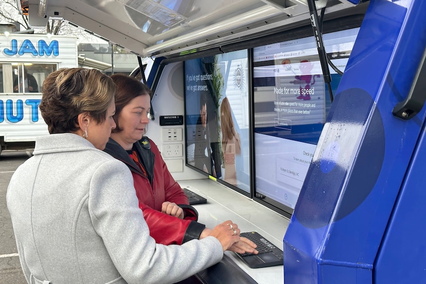 Two people using a pop-up information kiosk in a car park.