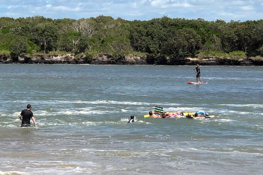Eight children being rescued by volunteer surf lifesavers at Currumundi Beach on the Sunshine Coast