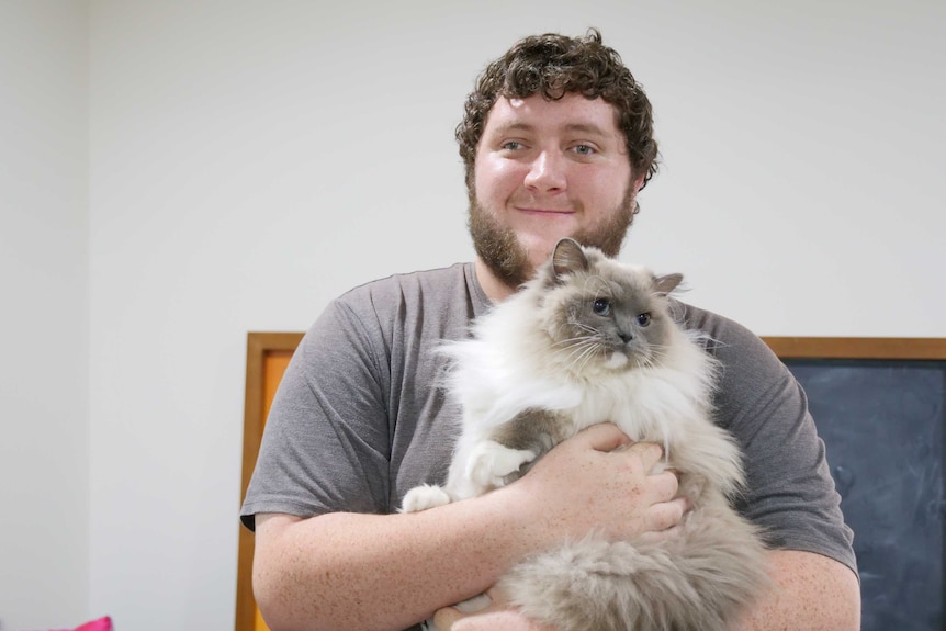 A man holds Doctor Leopold, the ragdoll cat.