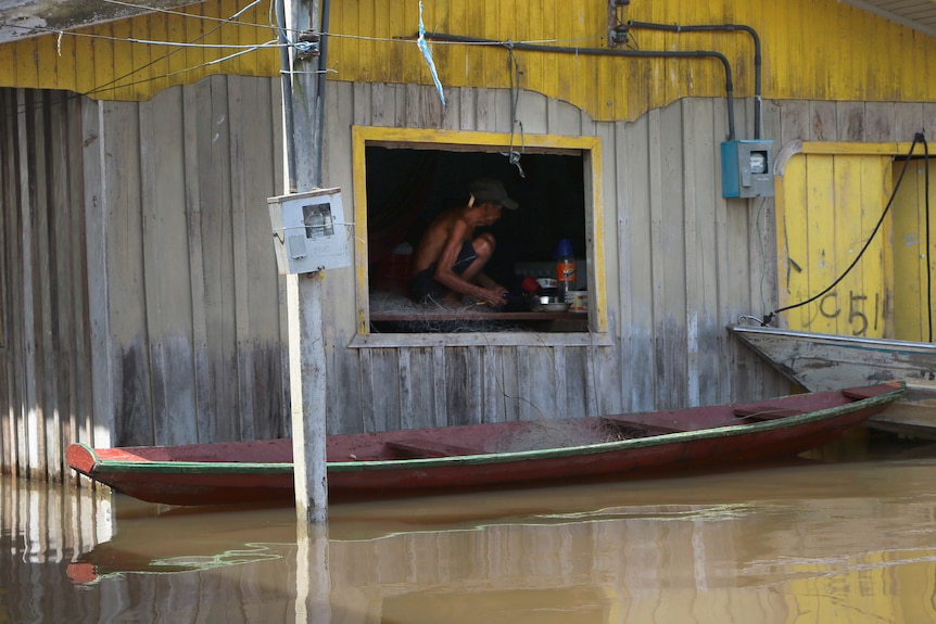 Un homme est assis dans sa fenêtre d'accueil lors d'inondations au Brésil