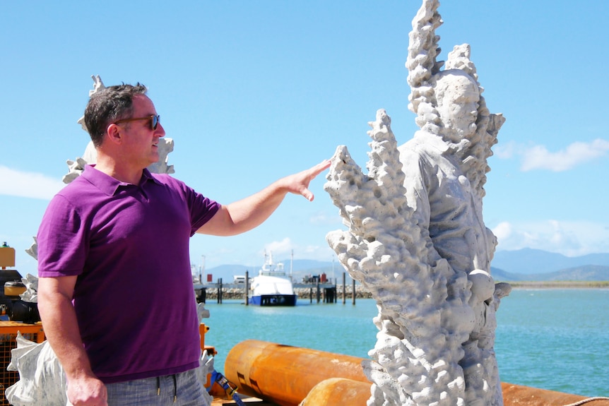 A man stands next to a sculpture on a ship deck