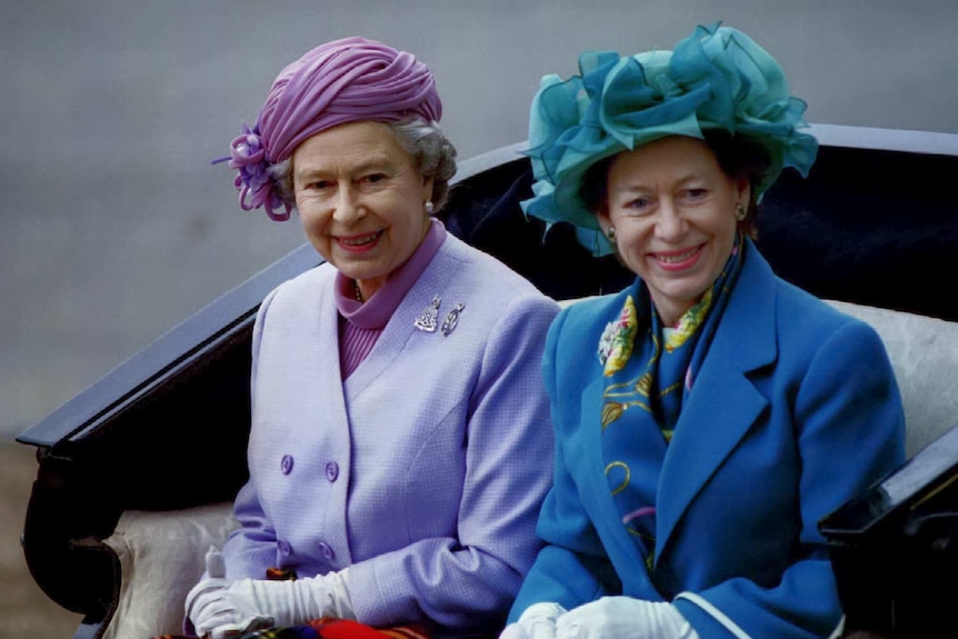 Queen Elizabeth II and Princess Margaret travel in an open carriage.
