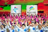 People in colourful outfits stand in front of banners that read Beijing 2022.