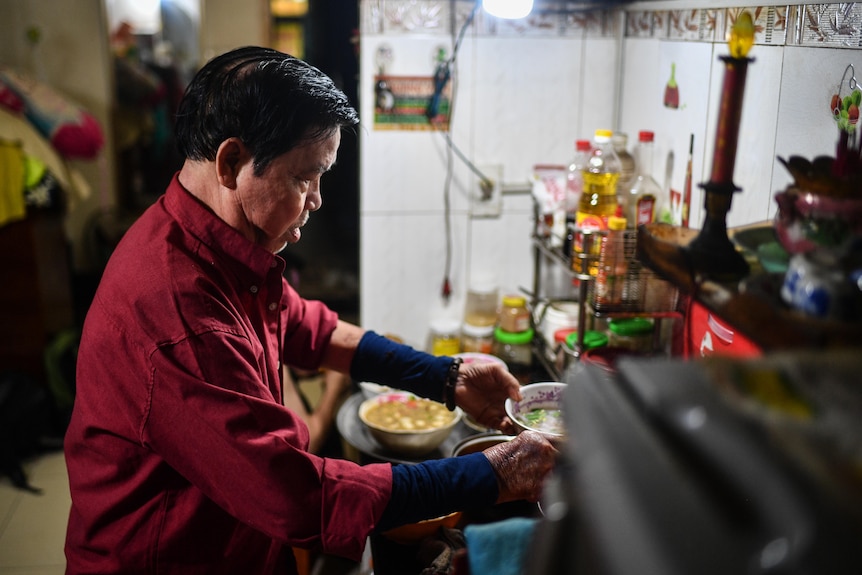 Binh Phan stands in the kitchen serving dinner.