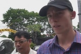 Jamie Murphy faces media as he walks with another person in Bali.