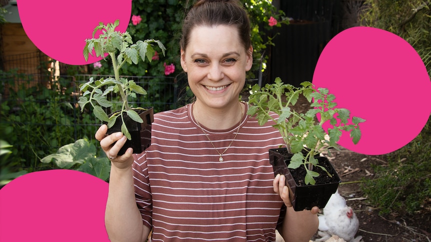 Woman holds two seedlings in pots in her Adelaide backyard.
