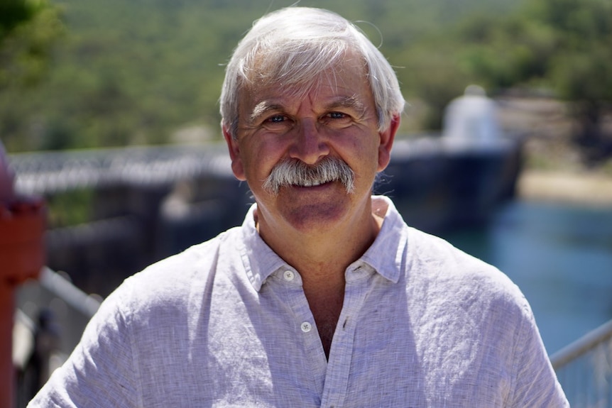 Man in hemp shirt in front of a dam