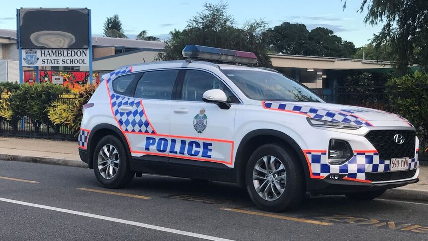 A police car is parked outside a sign for Hambledon State School