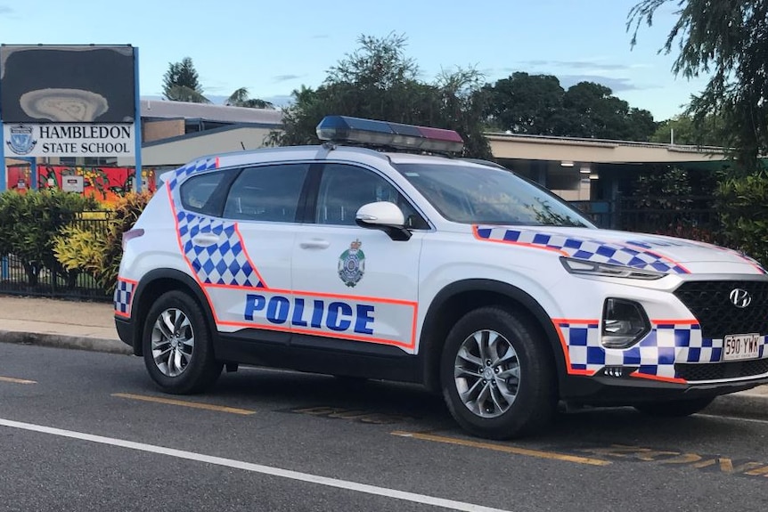 A police car is parked outside a sign for Hambledon State School