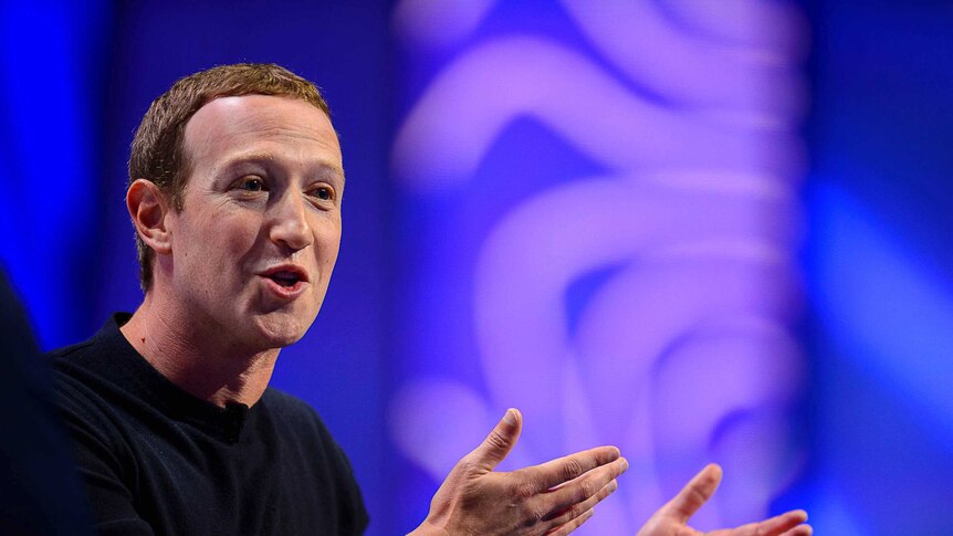 Facebook CEO Mark Zuckerberg gestures with his arms and smiles as he speaks.
