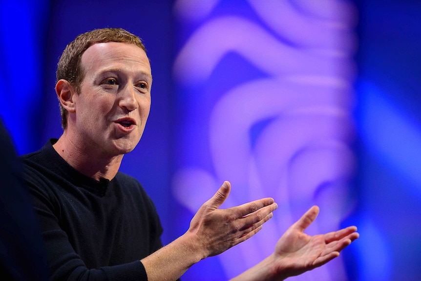 Facebook CEO Mark Zuckerberg gestures with his arms and smiles as he speaks.