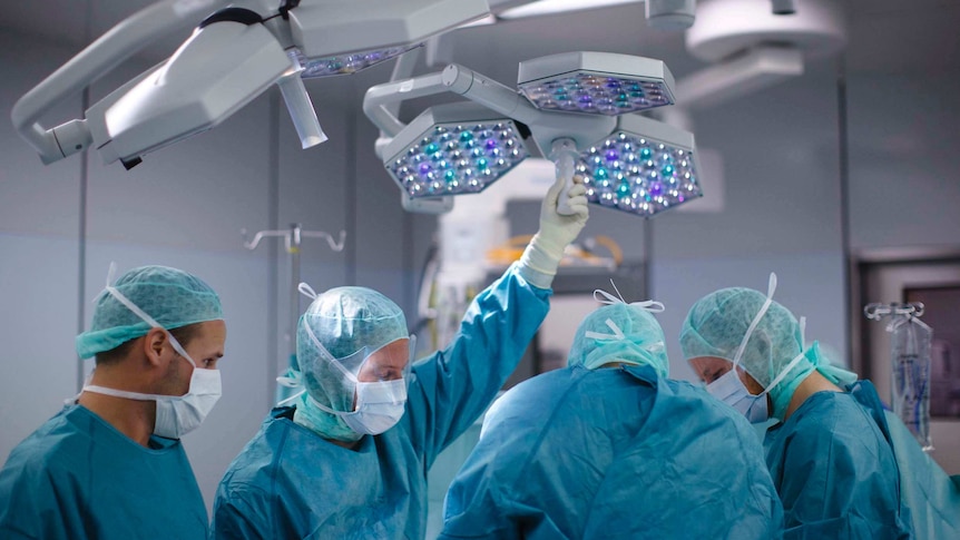 Doctors and medical staff prepare for surgery in an operating theatre.