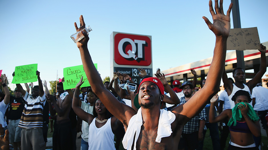 Residents of the US town of Ferguson hold their hands up to protest a police shooting