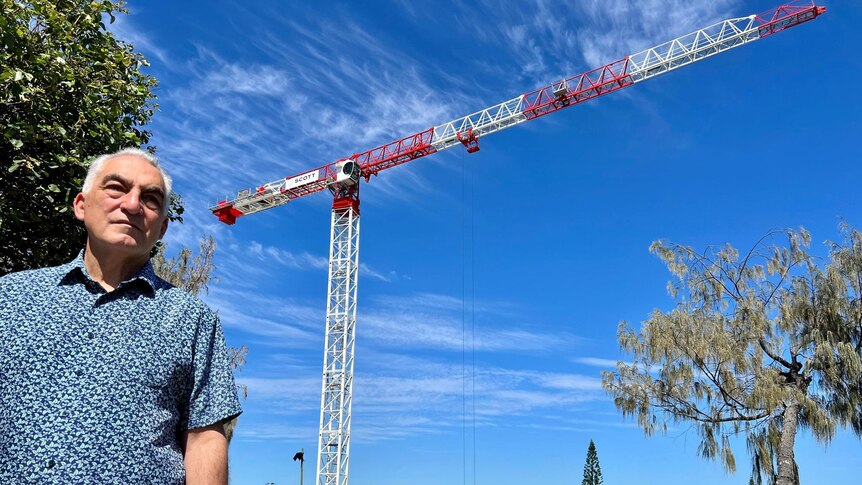 Man in collared shirt standing in front of crane