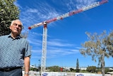 Man in collared shirt standing in front of crane