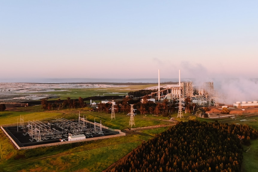 An aerial image of a power station with white towers and steam, against a blue-pink horizon.