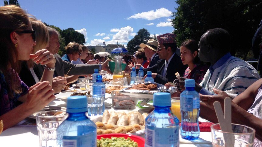 Attendees wearing various cultural dress share food on the lawns of Government House.