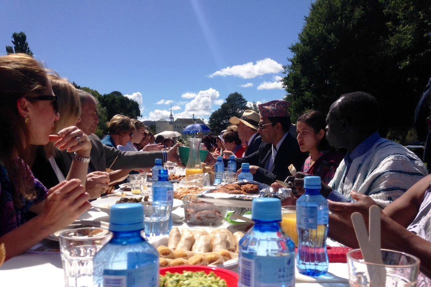 Attendees wearing various cultural dress share food on the lawns of Government House.